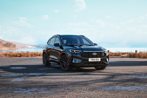 Une Ford Kuga noire de l'édition Black & White sur une route côtière avec la mer en arrière-plan